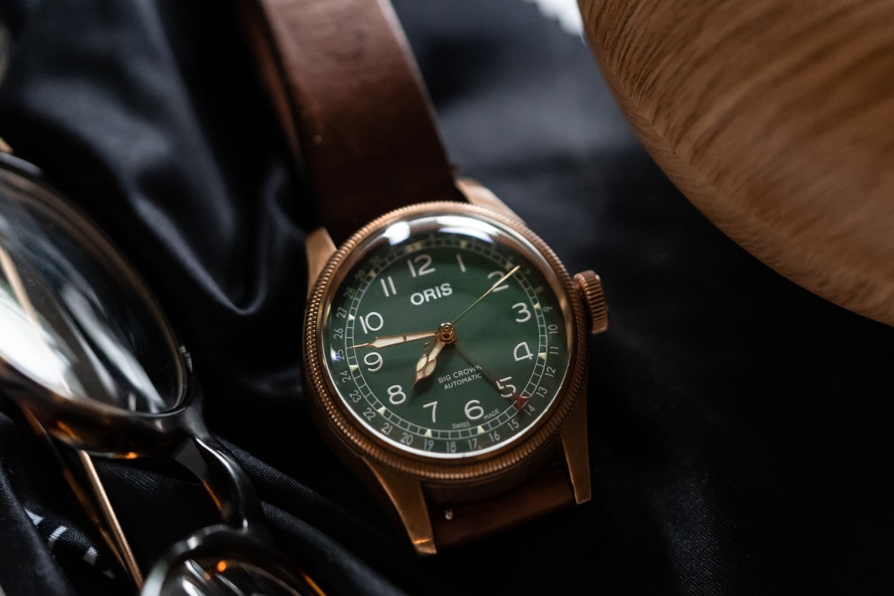 A green dial watch with arab numerals, brown leather strap, near the glasses. A green dial watch with arab numerals, brown leather strap, near the glasses.