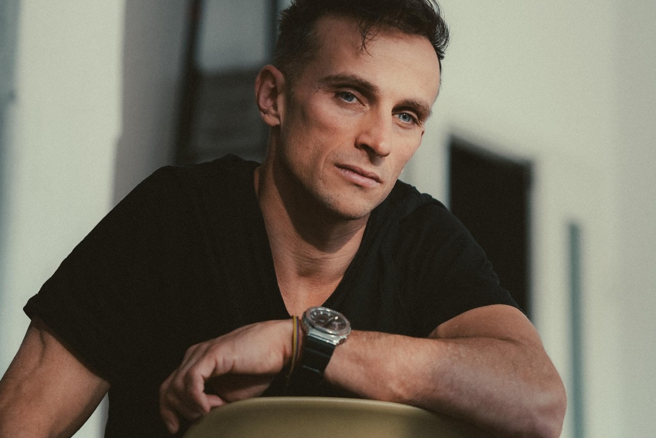A close-up of a comfortably dressed man wearing a luxury sports watch.