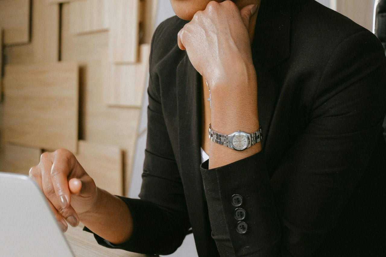 A close-up of a woman in professional attire wearing a dress watch.
